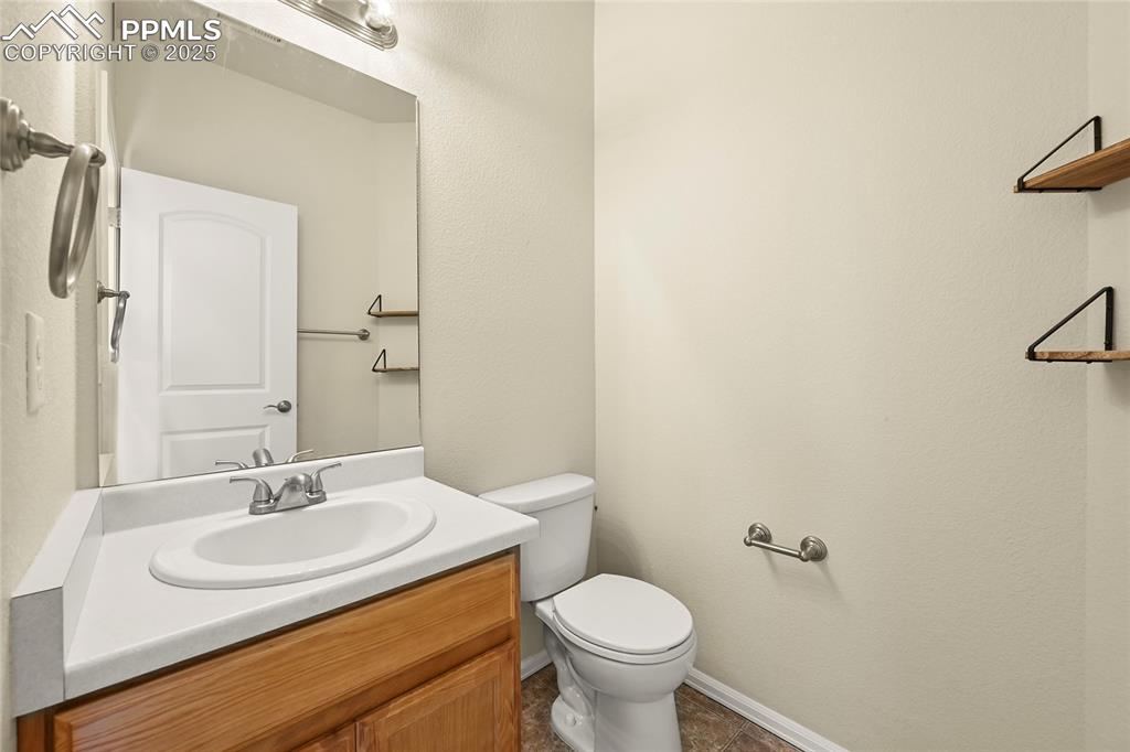 Image 12 of 28: Bathroom featuring vanity, a textured wall, and dark tile patterned floorin