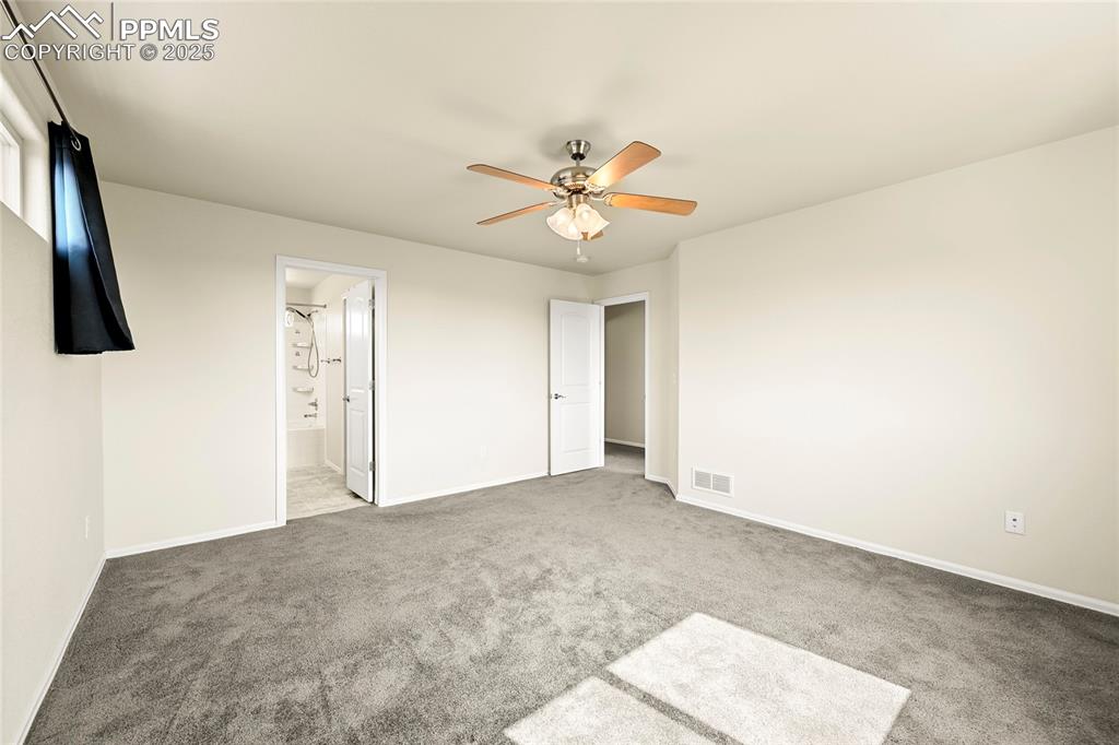 Image 15 of 28: Unfurnished bedroom with carpet floors, a ceiling fan, and ensuite bathroom