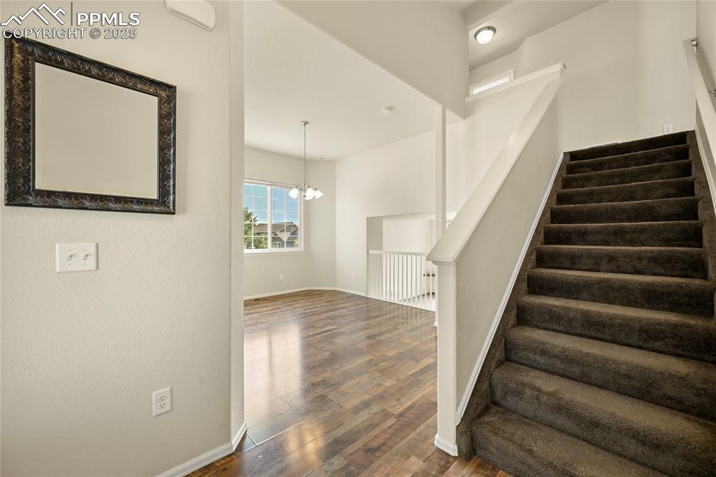 Image 3 of 28: Staircase featuring wood finished floors and a chandelier
