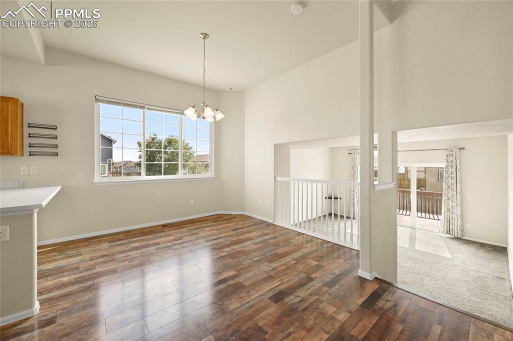Image 4 of 28: Unfurnished dining area featuring a chandelier and dark wood finished floor