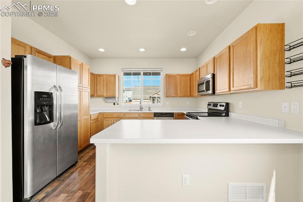 Image 6 of 28: Kitchen with stainless steel appliances, a peninsula, light countertops, re