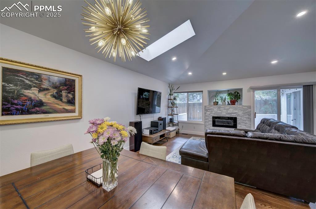 Image 12 of 40: Dining space with vaulted ceiling, a skylight, a fireplace, wood finished f