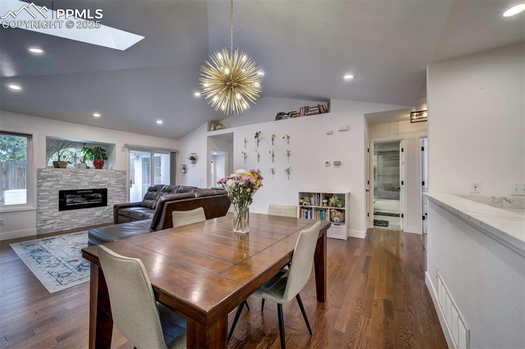 Image 13 of 40: Dining area featuring vaulted ceiling, a chandelier, recessed lighting, dar