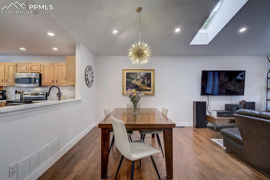 Image 15 of 40: Dining space featuring recessed lighting, a skylight, and dark wood-style f