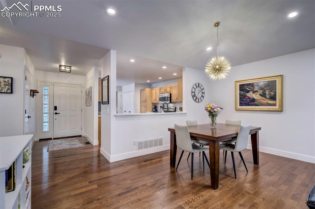 Image 17 of 40: Dining room featuring recessed lighting, dark wood-style floors, and a chan