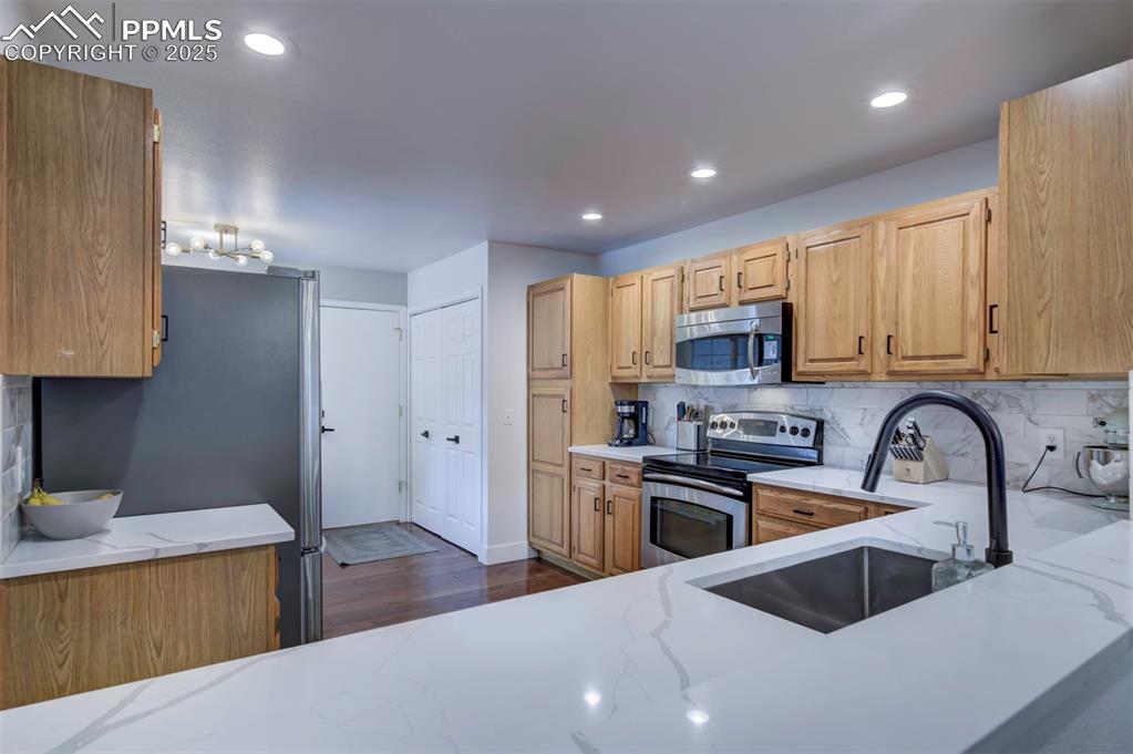 Image 18 of 40: Kitchen featuring decorative backsplash, stainless steel appliances, light