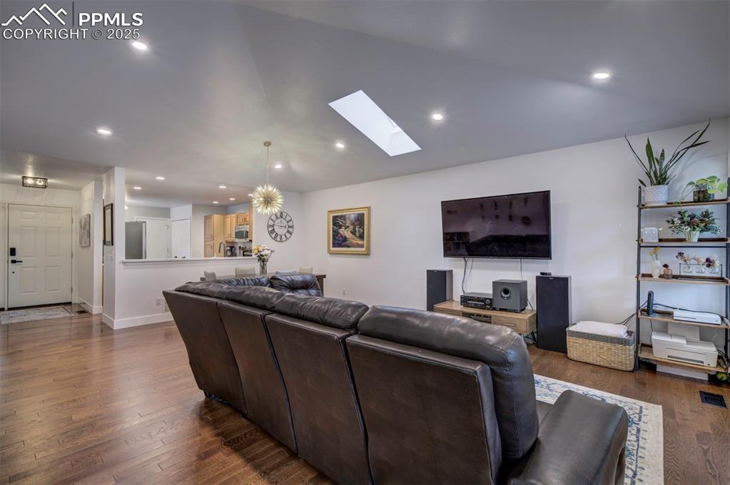 Image 19 of 40: Living room featuring a skylight, recessed lighting, dark wood-style floors