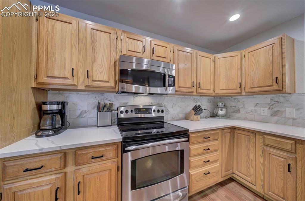 Image 24 of 40: Kitchen featuring appliances with stainless steel finishes, decorative back