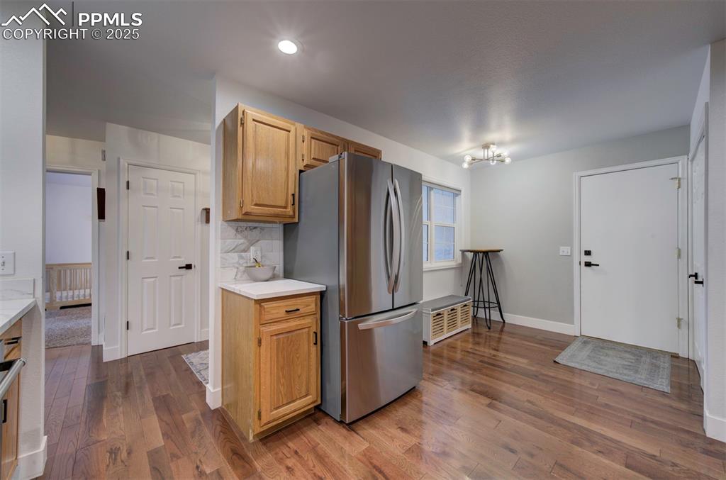 Image 26 of 40: Kitchen with light countertops, freestanding refrigerator, backsplash, and
