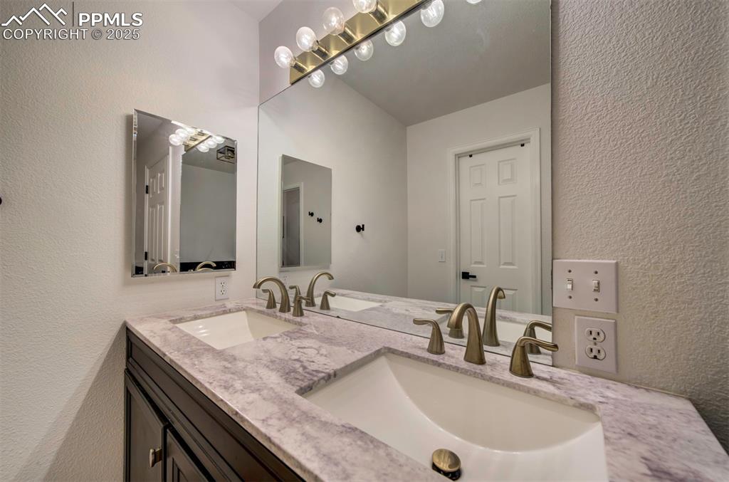 Image 31 of 40: Bathroom featuring a textured wall and double vanity