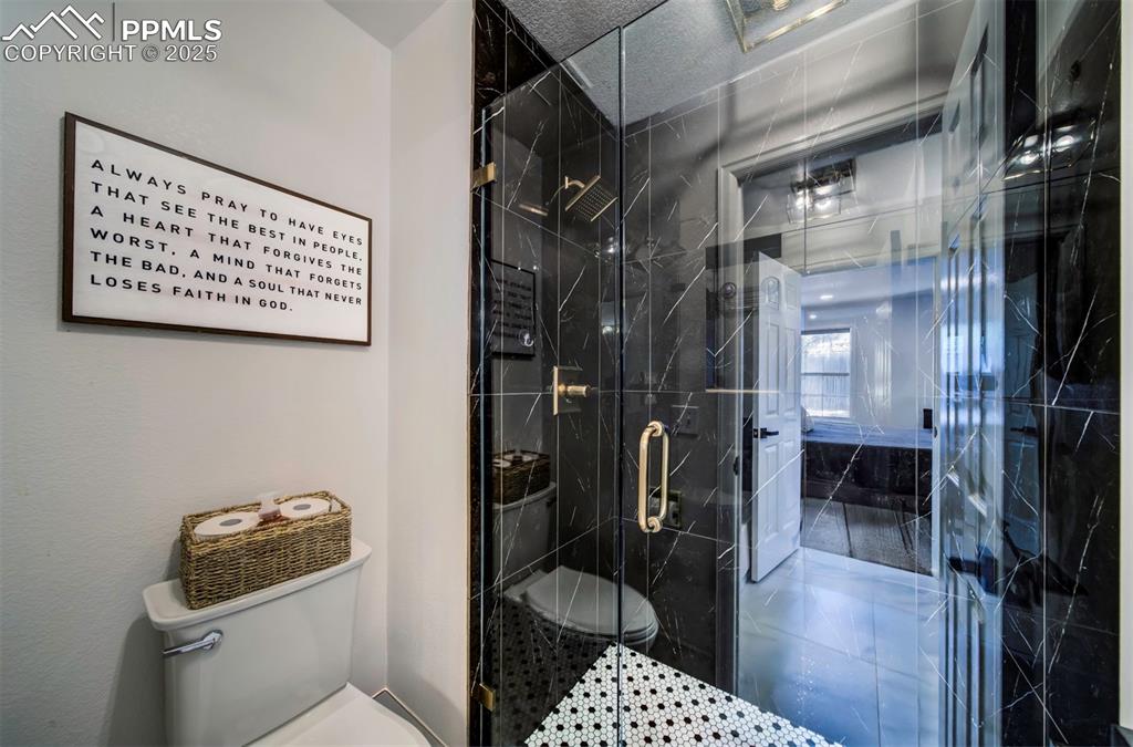Image 35 of 40: Full bath with toilet and a marble finish shower