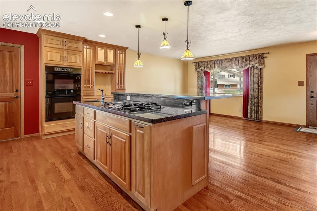 Image 4 of 30: Open Floor Plan, Oak Wood Flooring, Pendant Lighting Above The Breakfast Ba