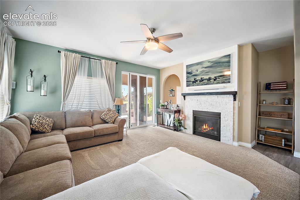 Image 13 of 49: Living room with carpet, walkout and gas fireplace.
