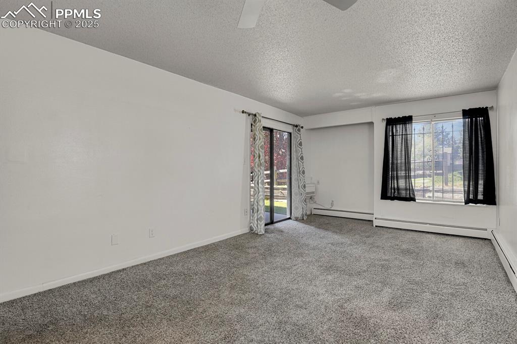 Image 4 of 17: Spare room with carpet floors, a textured ceiling, and a baseboard radiator