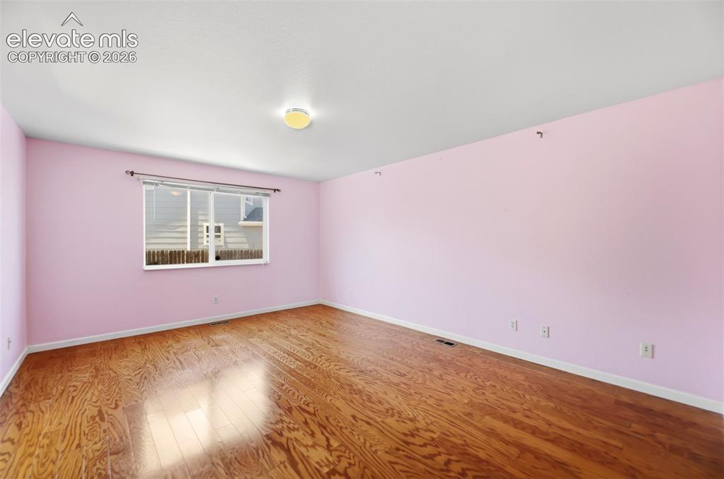 Image 15 of 50: Spacious room featuring wood-finish flooring, a bright window, and a ceilin