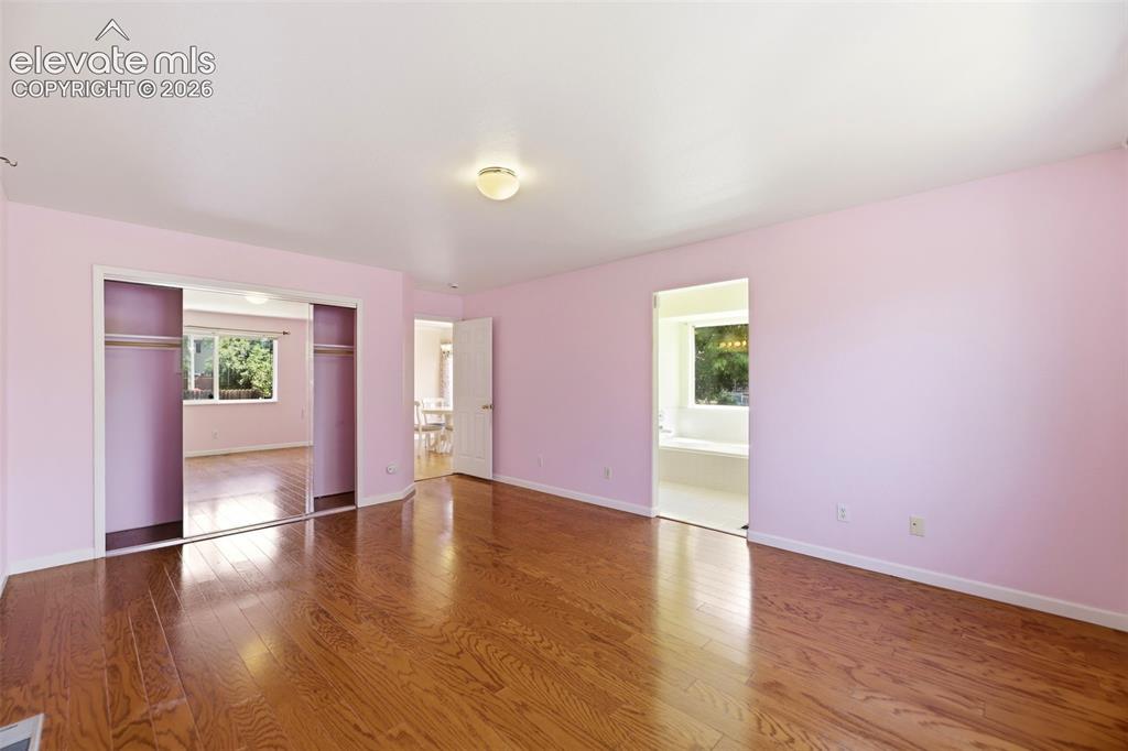 Image 17 of 50: Spacious room featuring hardwood flooring, light pink walls, and a ceiling-