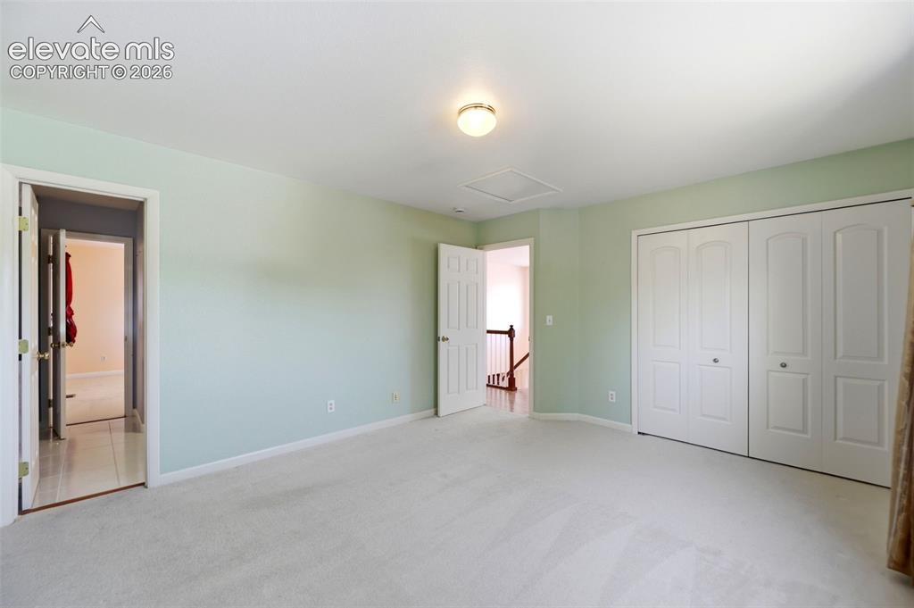 Image 23 of 50: Spacious room with light green walls and neutral carpeting