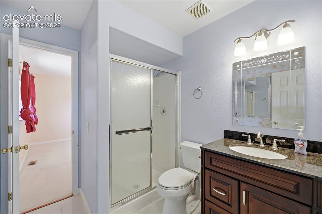 Image 24 of 50: Bathroom featuring a dark wood vanity with a granite countertop, undermount