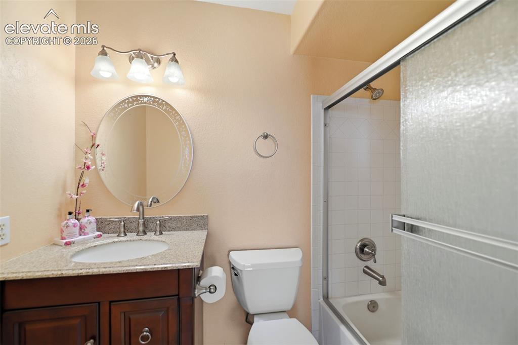 Image 29 of 50: Bathroom featuring a dark wood vanity with a light speckled countertop, an