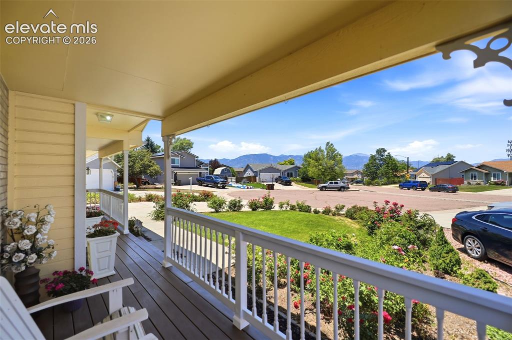 Image 3 of 50: Covered front porch with composite wood-finish flooring, white railing, and
