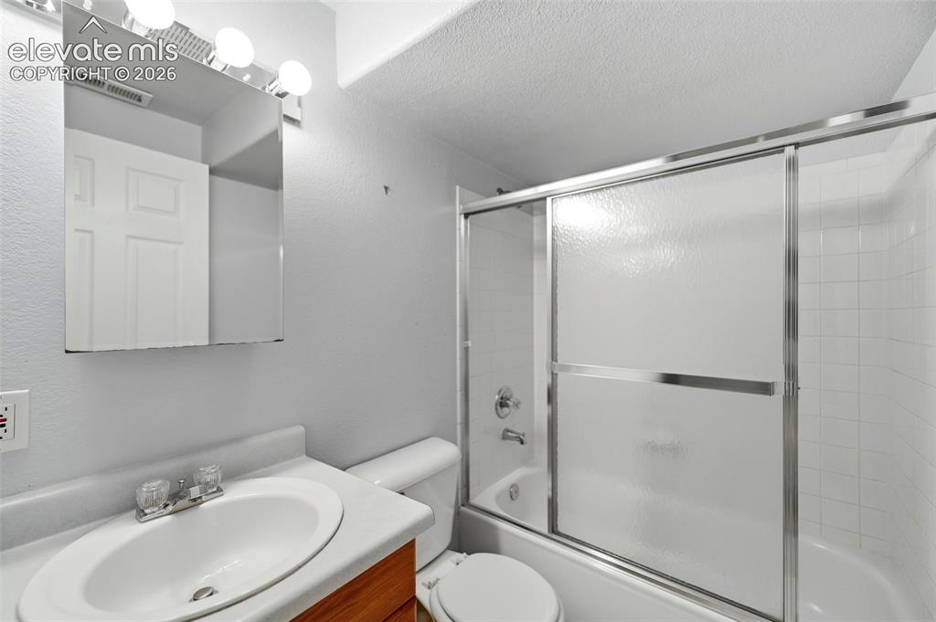 Image 33 of 50: Bathroom featuring a wood-finish vanity with an integrated sink, a mirrored