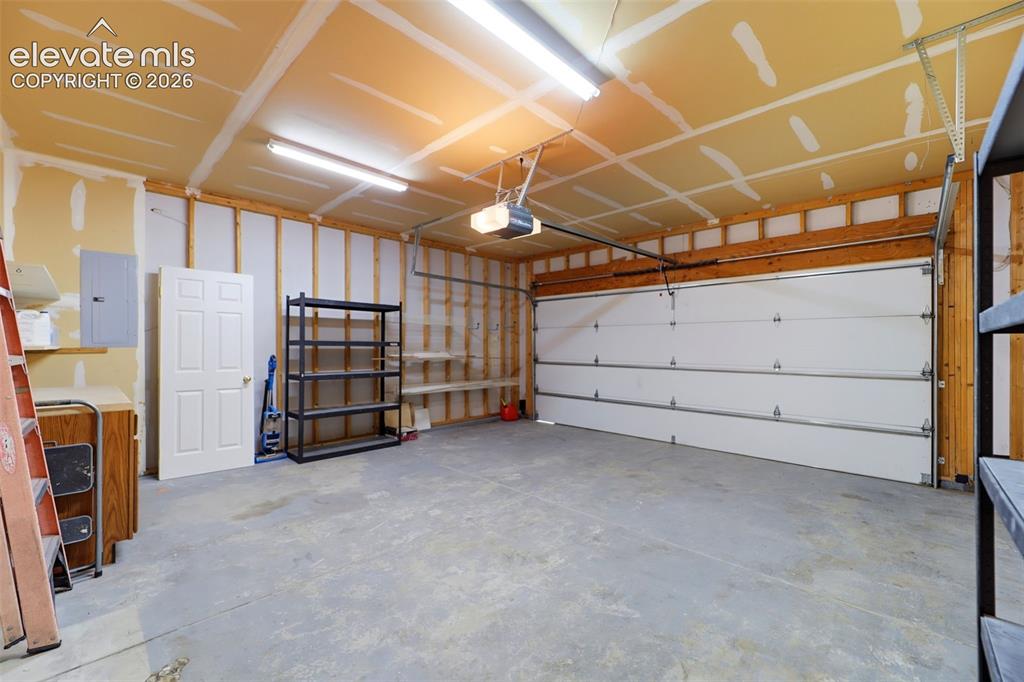 Image 36 of 50: Spacious garage featuring a concrete floor, overhead lighting, and an autom