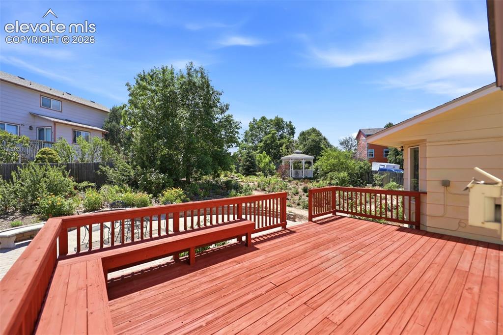Image 37 of 50: Spacious red-stained wood deck featuring integrated bench seating and match