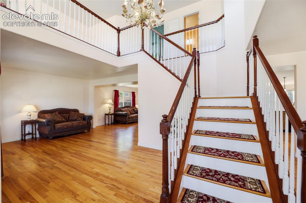Image 4 of 50: Two-story entry foyer featuring a grand staircase with wood-finish treads a