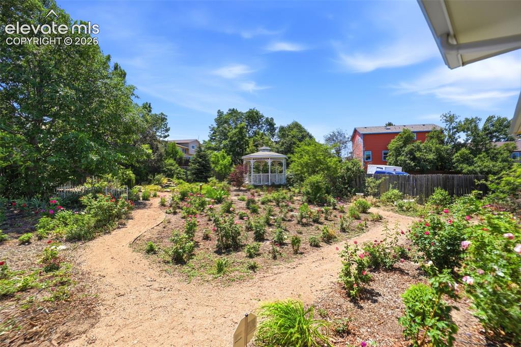 Image 40 of 50: Landscaped garden featuring a central white gazebo, multiple walking paths,