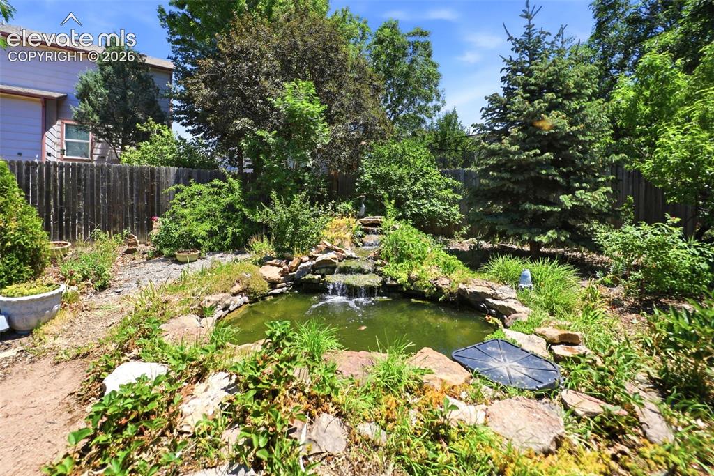 Image 42 of 50: Landscaped backyard featuring a multi-tiered rock waterfall and pond