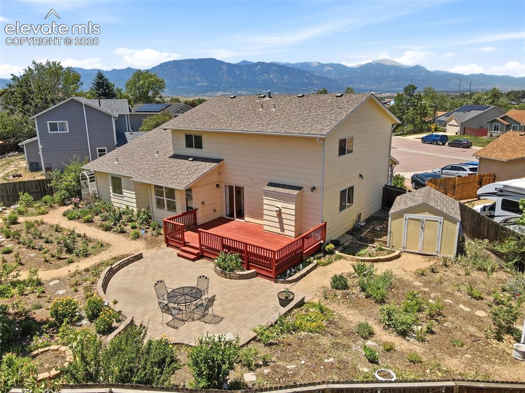 Image 43 of 50: Expansive backyard featuring a red wood-finish deck, a semicircular paver p