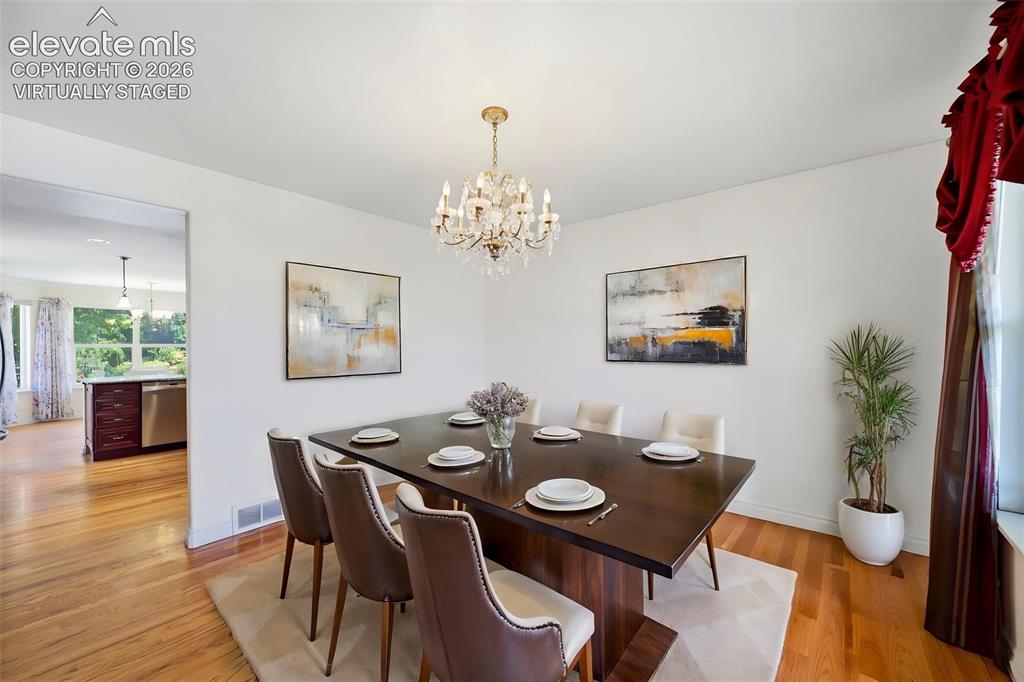 Image 6 of 50: virtually staged formal dining space featuring a chandelier, hardwood floo