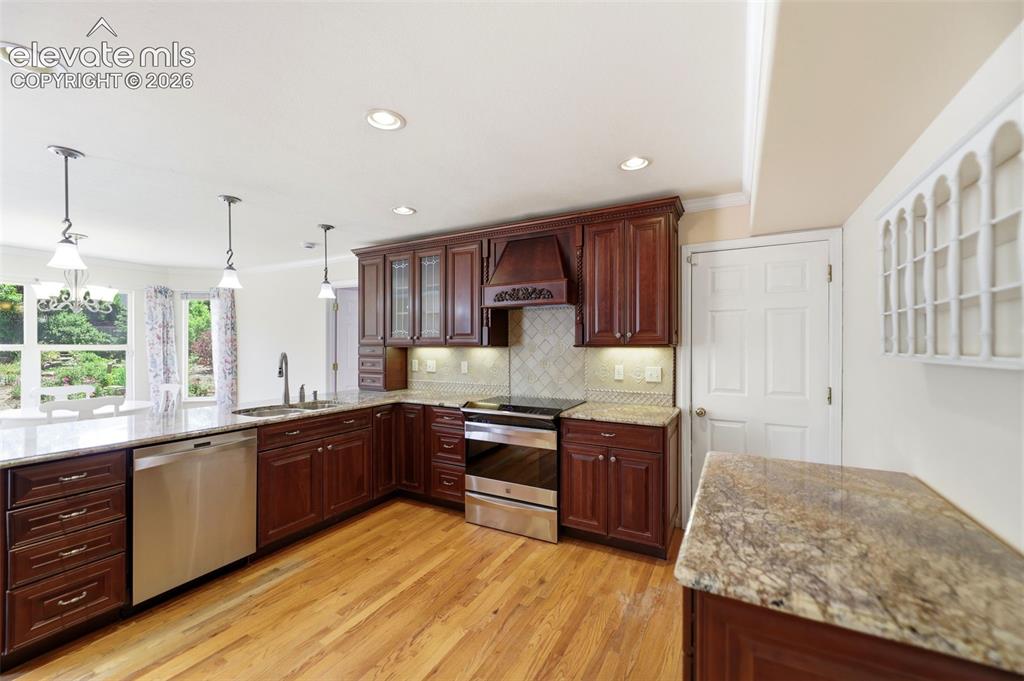 Image 7 of 50: Kitchen featuring rich wood cabinetry, granite countertops, stainless steel
