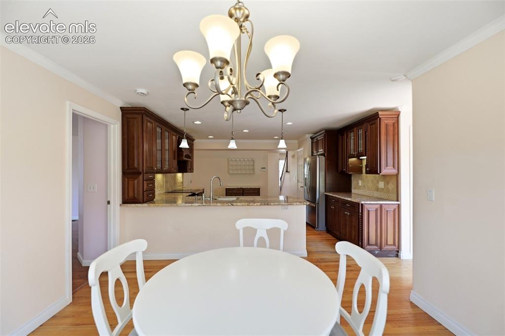 Image 9 of 50: Dining area featuring a chandelier with frosted glass shades, hardwood floo