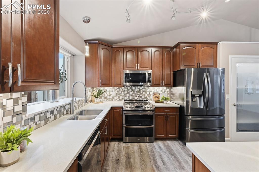 Image 11 of 50: Custom tile backsplash in the kitchen. All of the black stainless appliance