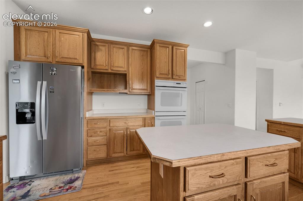Image 13 of 48: Kitchen Featuring Island, Double Oven, Refrigerator and Hickory Wood Cabine