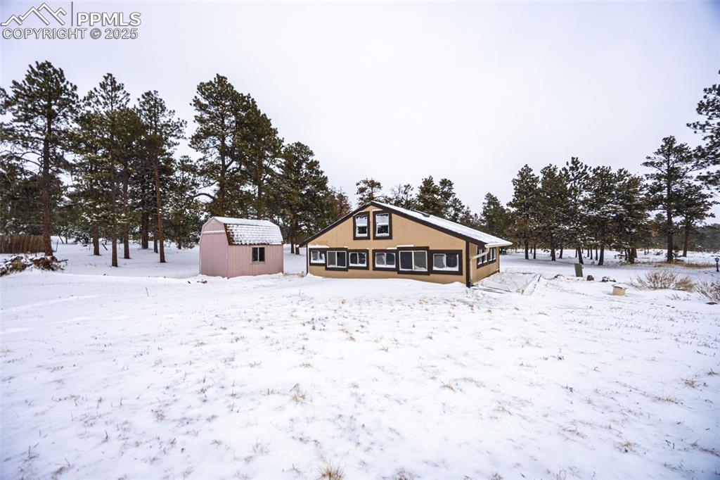 Image 8 of 36: Snow covered rear of property with an outdoor structure and a shed