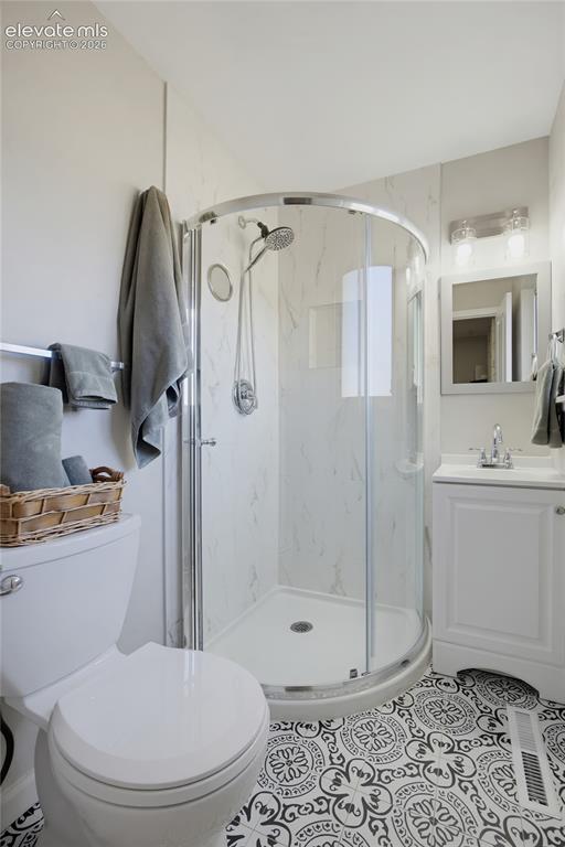 Image 19 of 29: Walk-in shower with curved glass enclosure, white vanity with integrated si