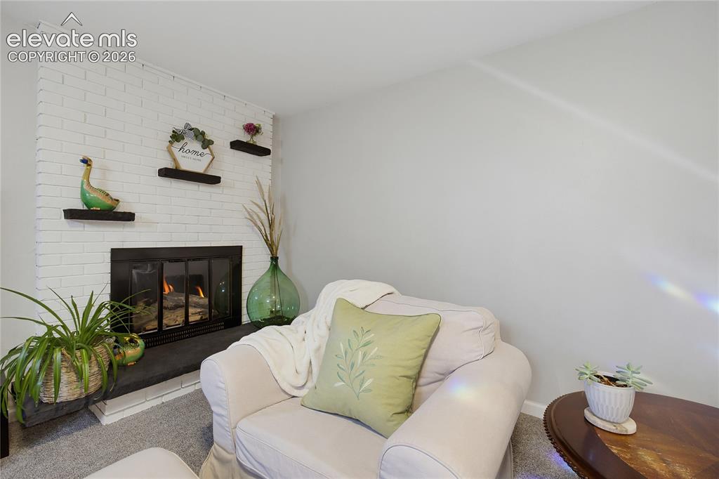 Image 23 of 29: Painted brick fireplace with a dark-framed firebox and hearth