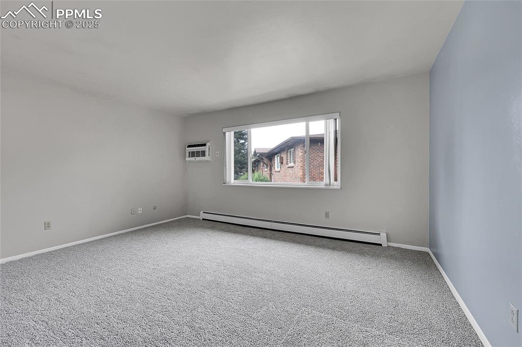 Image 22 of 33: Unfurnished room with a baseboard radiator, carpet floors, and a wall unit