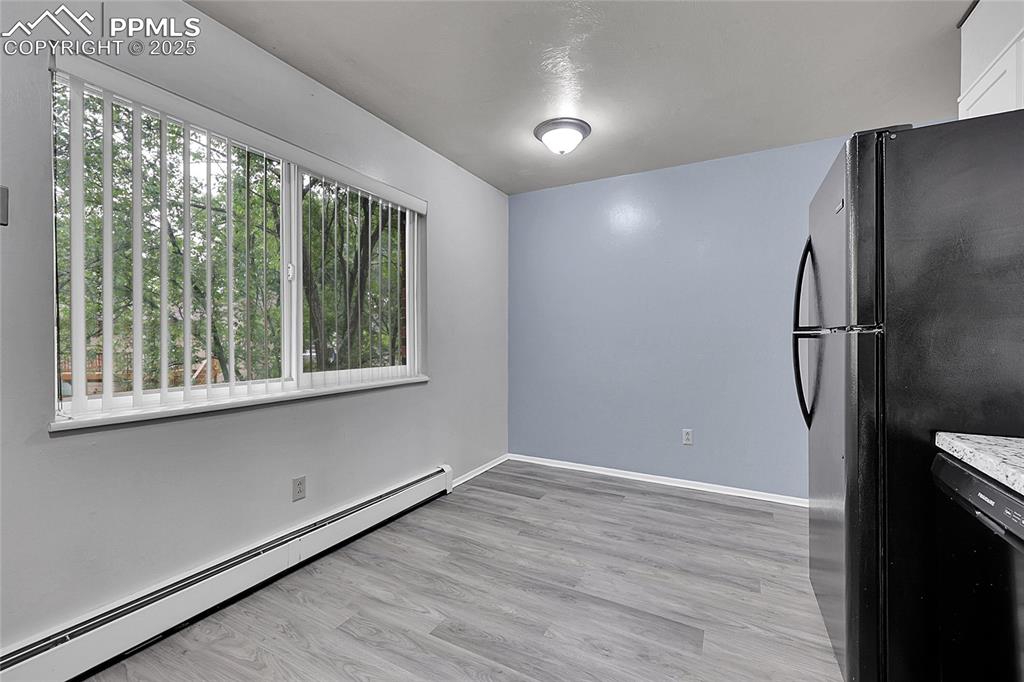 Image 27 of 33: Unfurnished dining area with baseboard heating and light wood-style floorin