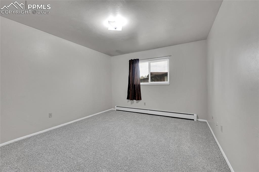 Image 31 of 33: Carpeted empty room with baseboard heating and baseboards