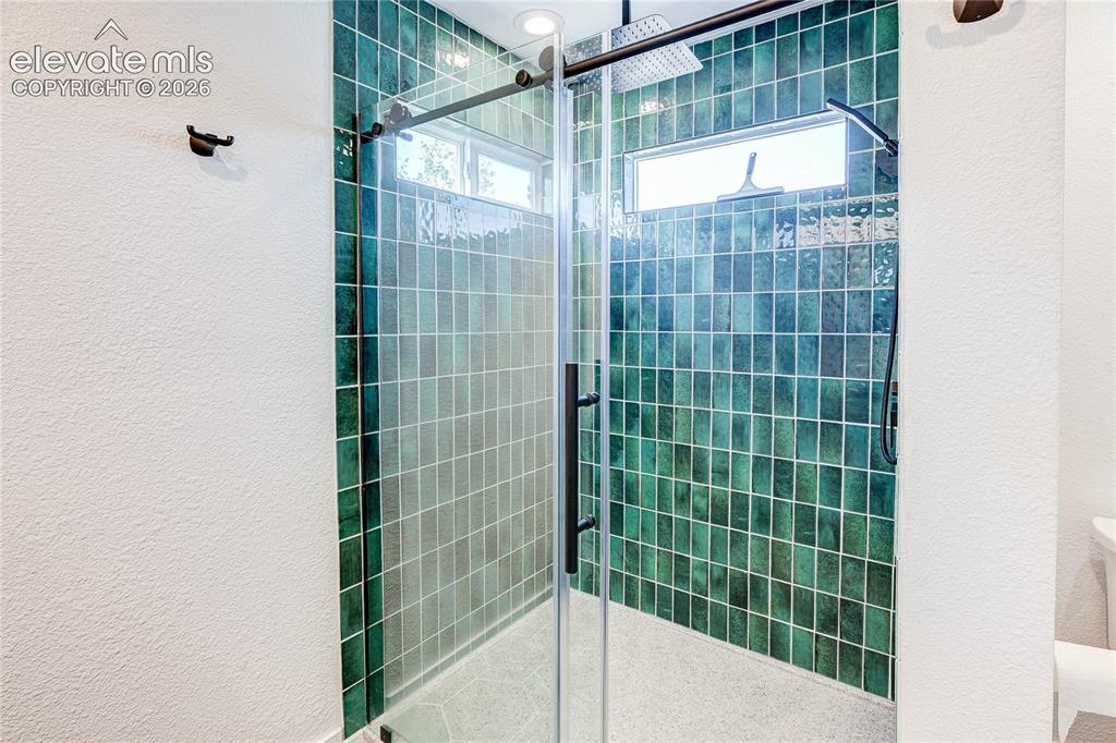 Image 19 of 42: Beautifully remodeled primary bath with 2 sinks and large walk-in shower.