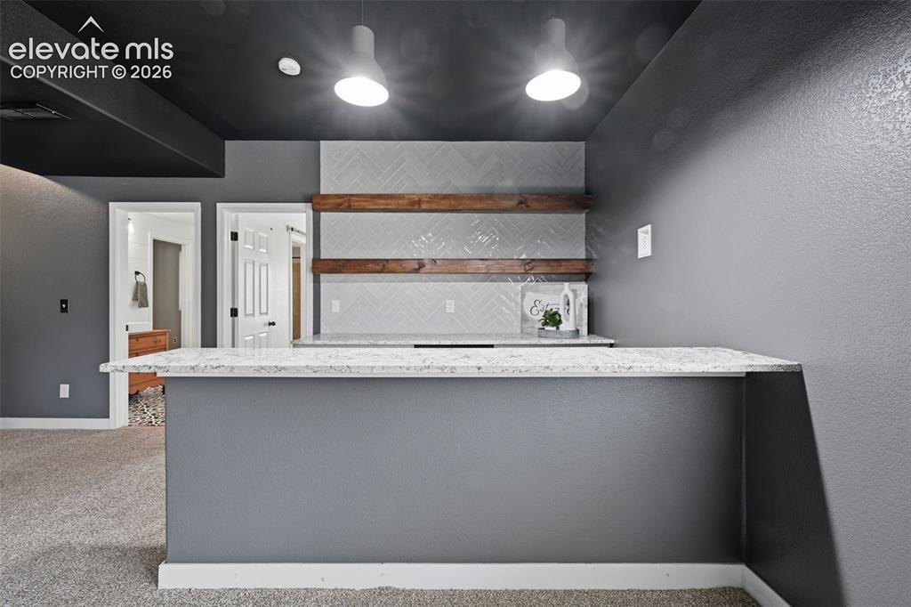 Image 40 of 49: Basement wet bar with upgraded counters, open shelving and wine cooler!