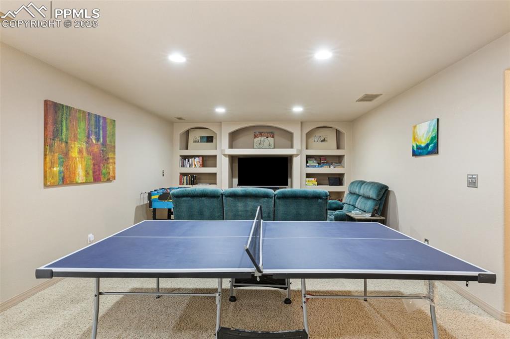 Image 18 of 27: Playroom featuring built in shelves, carpet flooring, and recessed lighting