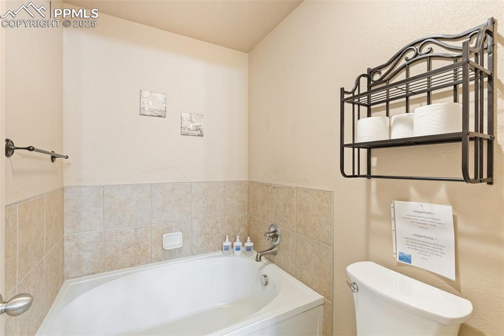 Image 23 of 27: Full bathroom featuring a bath and a textured wall