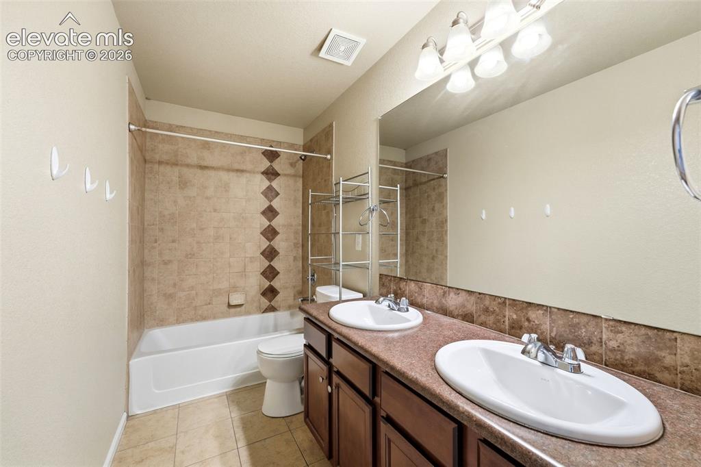 Image 14 of 33: Dual-sink vanity with wood-finish cabinetry and stone countertops, paired w