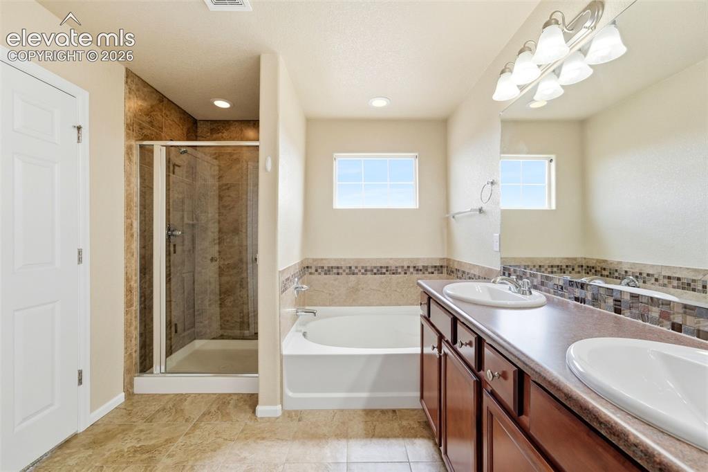 Image 20 of 33: Bathroom featuring a dual-sink vanity, built-in bathtub, glass-enclosed sho