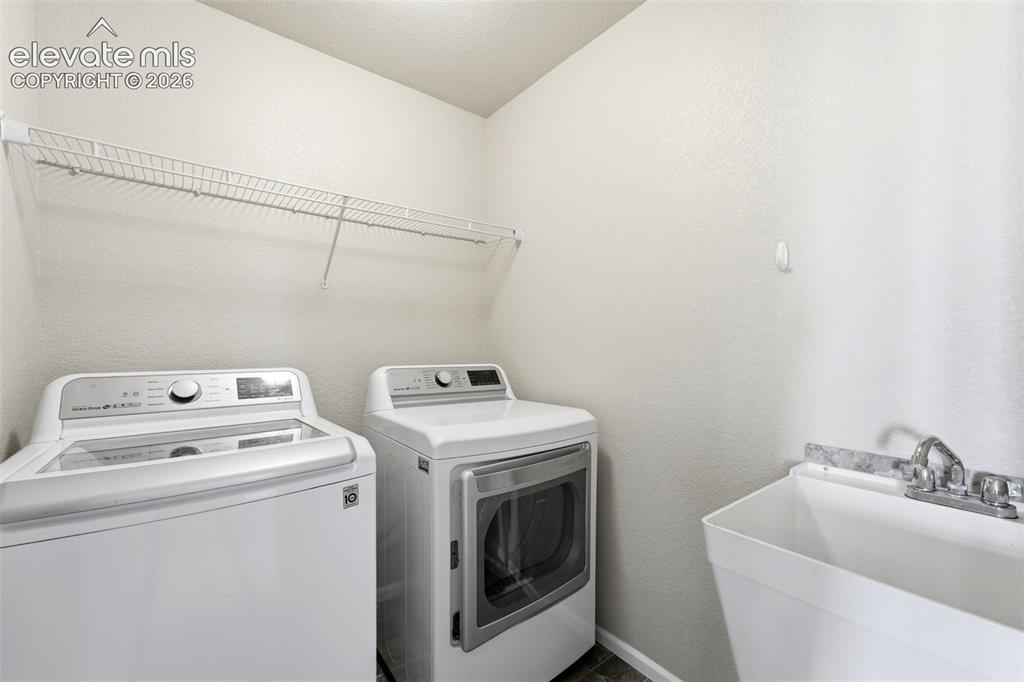 Image 23 of 33: Upstairs Laundry area featuring a utility sink, a wall-mounted wire shelf, 