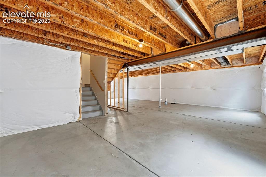 Image 24 of 33: Open-concept unfinished basement with concrete flooring, exposed wood joist